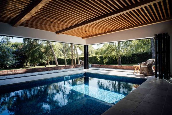 Contemporary swimming pool extension with timber cladding and garden views in Buckinghamshire